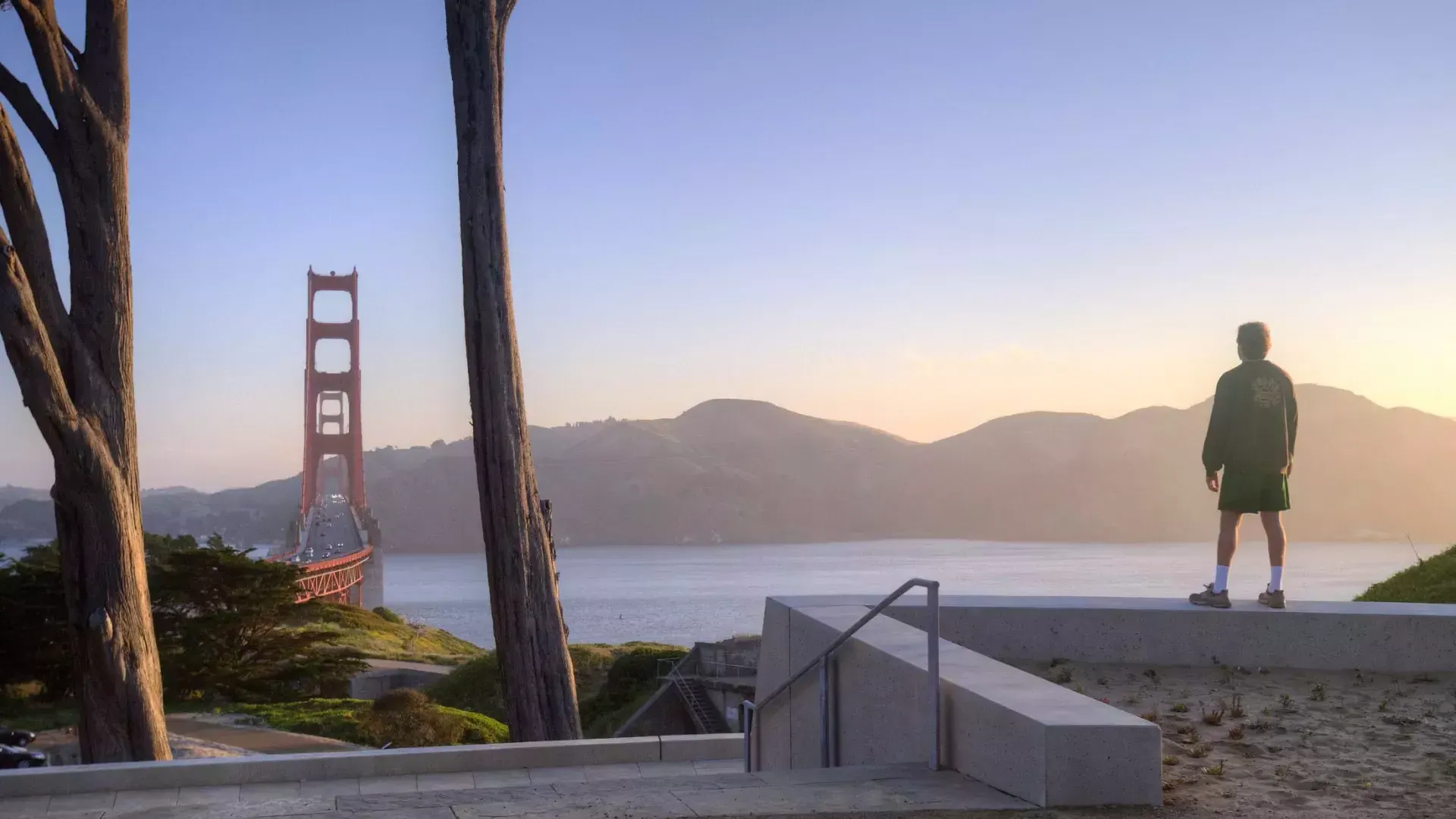 한 남자가 산을 배경으로 Golden Gate Bridge 내려다보고 있습니다.